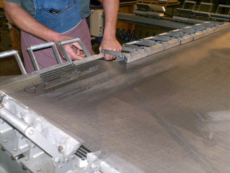 Wire mesh being tensioned on a clamping table